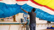 Lucas et Geoffrey de dos, en train de déployer une voile de parapente dans leur atelier